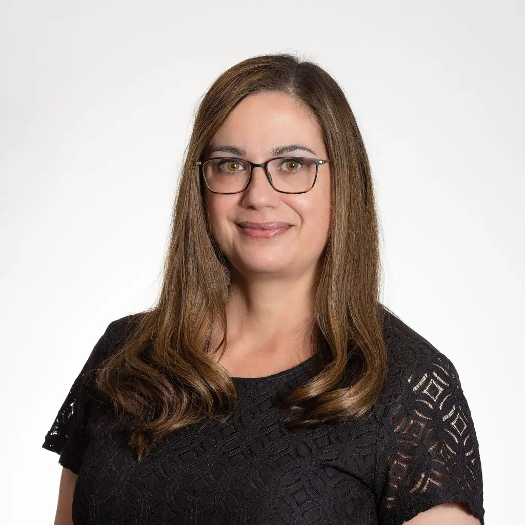 A woman in black shirt and glasses smiling for the camera.